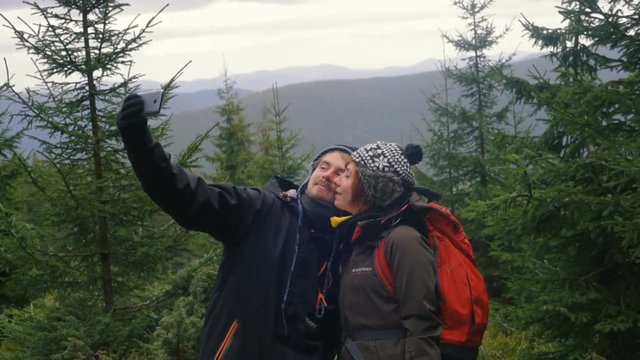 young loving couple taking selfie in mountains using smartphone