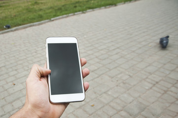 Man hand using a smart phone outdoors. The man sitting on the benchand wait for the meeting with a person