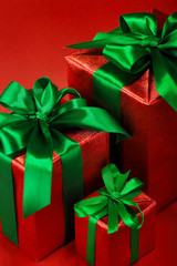 Red gift boxes with green ribbons and bow on red holiday background . Merry christmas card. Winter xmas theme.Boxing day