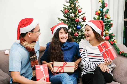 Young asia man and women holding gift boxes, talking and smiling with happiness in Christmas party, friends Christmas party celebration