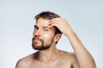 Obraz premium Man with a beard on a light background, cosmetic face cream, beauty, health