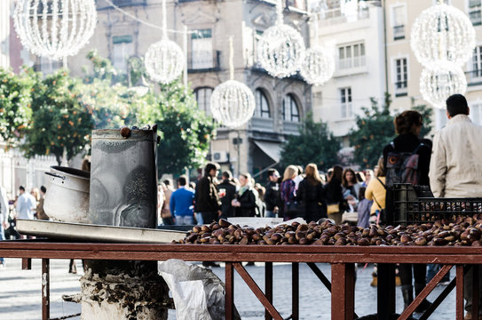 Roasted chestnuts stand in Seville downtown during Christmas eve in a crowded street