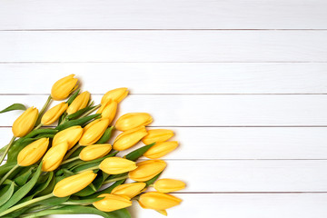 Bouquet of yellow tulips on white wooden background. Top view, copy space