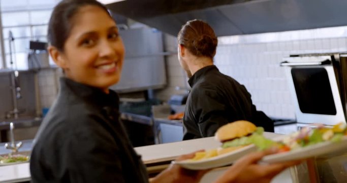 Male chef handing over meal plates to waitress 