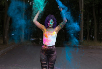 Wonderful young woman with purple hair tossing up color Holi powder