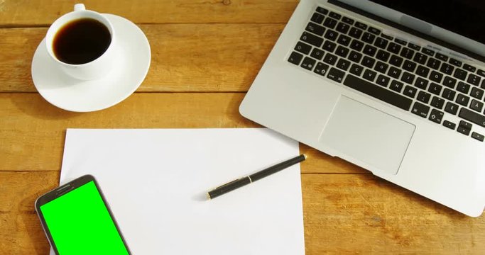 Laptop, blank paper, mobile phone, pen and coffee on table 