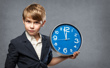 Serious 7 Year old Boy, Holding a blue Big Clock, just minutes before midnight: either, he is...