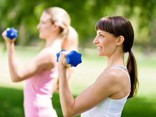 Portrait of cheerful women in fitness wear exercising with dumbbell