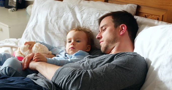 Father and baby boy relaxing in bedroom 