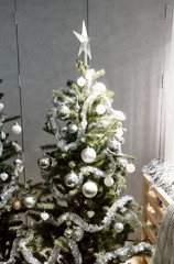 White and silver decorative Christmas tree with tinsel garland, glitter balls, and silver star