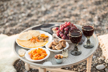 Outdoors picnic with wine, cheese, grapes and dried fruits