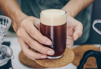 Barista holding and serving nitro cold brew coffee. - obrazy, fototapety, plakaty
