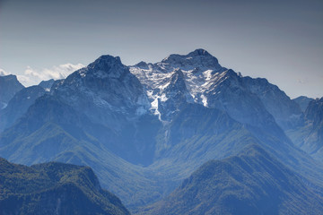 Snow covered Triglav and Rjavina peaks from north with pine forests in deep glacial Vrata, Kot and...