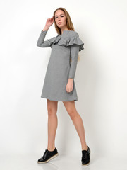 Young beautiful woman posing in new fashion gray dress in a cage full body