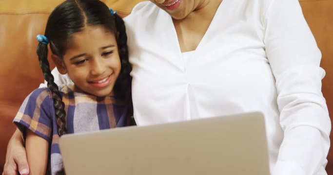 Grandmother and granddaughter using laptop in living room 