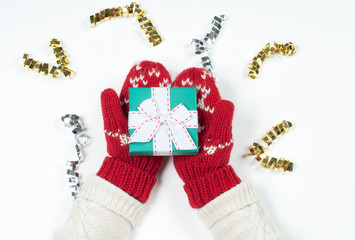 Female hands holding christmas gift in red mittens