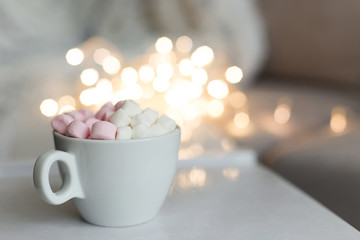 Cup of hot chocolate and marshmallow in the background of Christmas decorations.