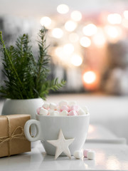 Cup of hot chocolate and marshmallow in the background of Christmas decorations.
