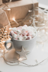 Cup of hot chocolate and marshmallow in the background of Christmas decorations.