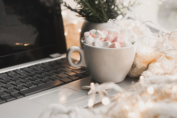 Cup of hot chocolate and marshmallow in the background of Christmas decorations.