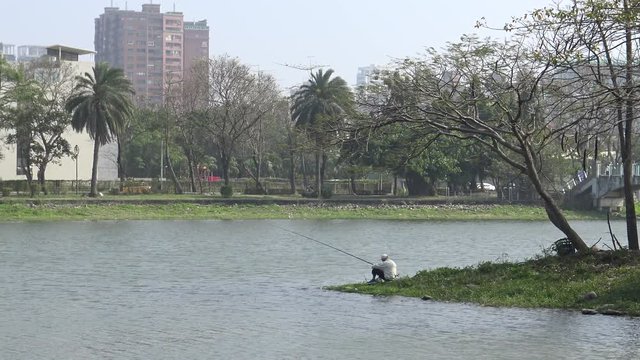 4k, Old Asian fisherman with a fishing rod on paceful lake in the Kaohsiung city-Dan