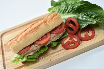 closeup photo of sandwich with tuna and vegetables on rye bread on wood background