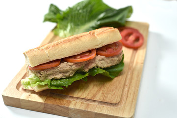 closeup photo of sandwich with tuna and vegetables on rye bread on wood background