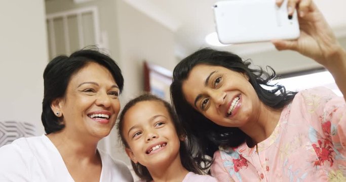 Multi-generation mixed-race family taking selfie with mobile phone in living room 