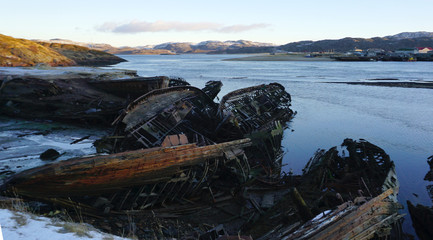 wrecked fisherman ship on the coast with mountain background in Teriberka