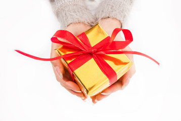 Female hand holding golden box present with red bow