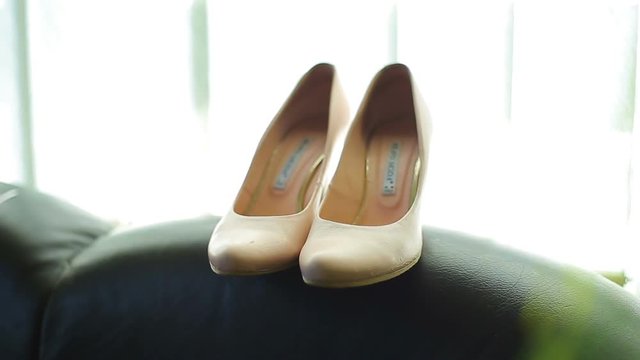 Close up of a brides wedding shoes displayed on a bed