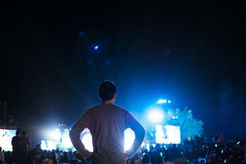 a man with crowded people enjoying outdoor night music festival