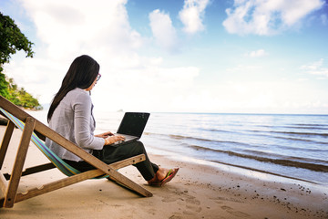 Business woman using a laptop beside the beach