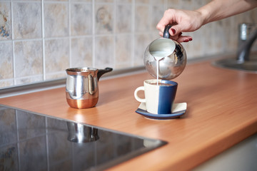 Cooking coffee in traditional copper turkey on a stove - kitchen interior