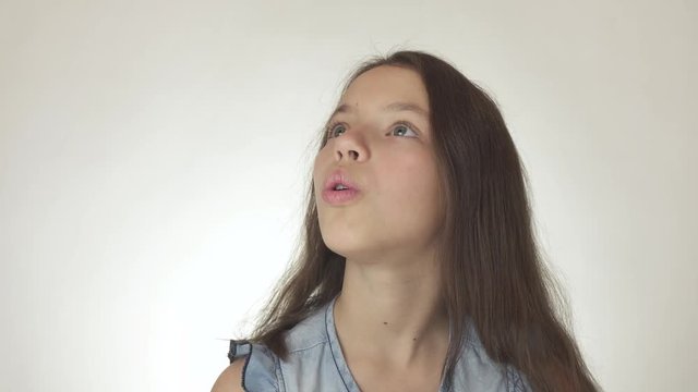 Beautiful happy teenage girl looks up and is surprised close-up on white background stock footage video