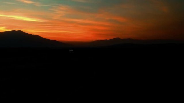 Panning aerial shot of mountains silhouetted against a sunset zooming out ALTERNATE VERSION