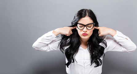 Young woman blocking her ears on a solid background