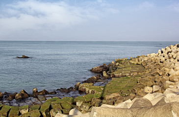 Coastline protection by wall made with huge concrete blocks and tetrapods, preventing sea erosion of land at Anjuna beach in Goa, India