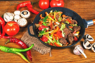fried meat with vegetables on a wooden table