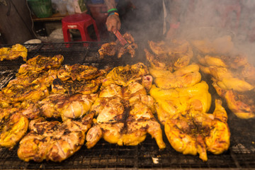 Samut Prakan, Thailand - November, 18, 2017 : Grilled chicken BBQ grilled on burning charcoal on display street food shop in festival night time at Samut Prakan, Thailand.