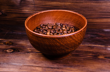 Fototapeta na wymiar Roasted coffee beans in bowl on wooden table