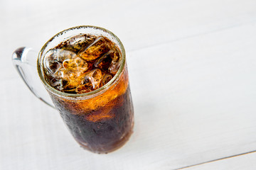 Glass of cola with ice on wood baord