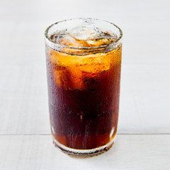 Glass of cola with ice on wood baord