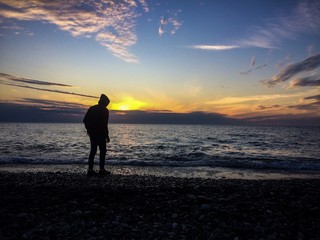 Fototapeta premium the guy at sunset near the sea