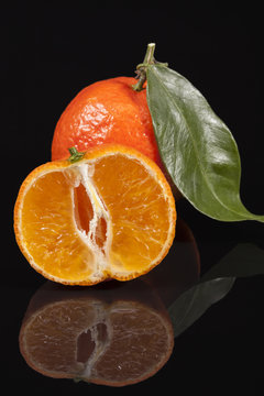 Fruits of mandarin orange ,whole and cut, on black background