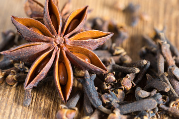 Nahaufnahme von Gewürznelken und Sternanis auf rustikalem Holzhintergrund © mofupic