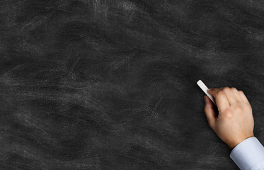 Naklejka premium Black chalkboard with hand holding chalk