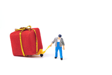 Miniature courier moving a Christmas  red present  on a pallet truck