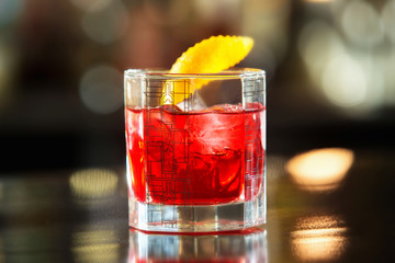 Closeup glass of red negroni cocktail at bar counter background.