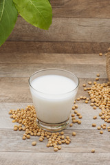 Glass with soy milk and soy bean on wooden background